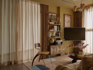 a living room with a television and a chair at LangX Ecopark Sky Forest - Dolce Apartment in Kim Quan