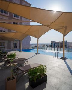 a large yellow umbrella over a patio with a pool at Levatio Suites Muscat, a member of Radisson Individuals in Muscat
