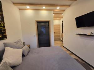 a bedroom with a bed and a flat screen tv at Scheuneria, Gästehaus in Dockweiler