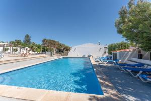 a swimming pool with chairs and a skate ramp at Villas 19 Estrellas in Cala en Bosc