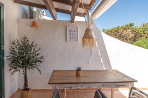 a wooden table on a patio with a potted plant at Villas 19 Estrellas in Cala en Bosc