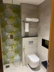 a bathroom with a toilet and a wall with leaves at Crown Residency in Kanyakumari