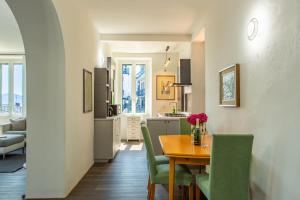 a kitchen and dining room with a table and green chairs at Simo House Stunning Lake View Balcony AC in Carate Urio