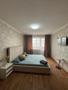 a bedroom with a large bed and a window at N40 Apartment in Pavlodar