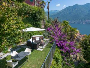 a garden with chairs and an umbrella and purple flowers at Simo House Stunning Lake View Balcony AC in Carate Urio