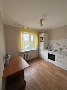 a kitchen with white appliances and a wooden floor at N40 Apartment in Pavlodar