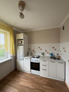 a kitchen with white cabinets and a sink at N40 Apartment in Pavlodar