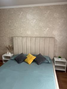 a bed with three pillows on it in a bedroom at N40 Apartment in Pavlodar +1 photo