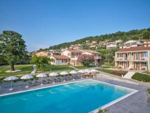 a resort pool with chairs and umbrellas at Residence Green Park in Torri del Benaco