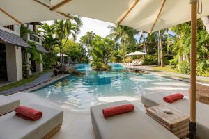 a swimming pool with two beds and an umbrella at Muang Samui Spa Resort in Chaweng