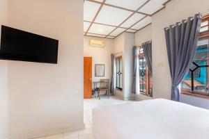 a bedroom with a bed and a tv on a wall at Agni Homestay in Yogyakarta