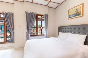 a bedroom with a large bed and windows at Agni Homestay in Yogyakarta