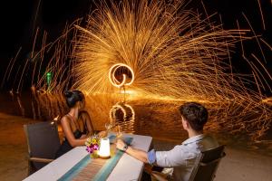 a man and woman sitting at a table in front of fireworks at Muang Samui Spa Resort in Chaweng +89 photos