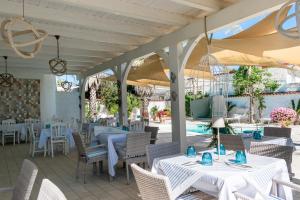 a restaurant with white tables and chairs and a pool at Marechiaro Pool & Restaurant in Paestum