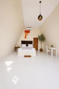 a white attic bedroom with a bed and a table at Jungle safari inn in Udawalawe