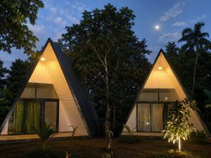a house with two triangular roofs with the moon in the background at Jungle safari inn in Udawalawe