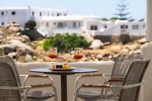 two glasses of wine and a plate of food on a table at Arocaria Mykonos in Mikonos