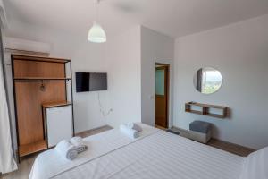 a white bedroom with a large bed and a tv at Sunny Hotel in Sarandë