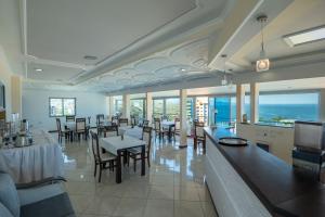 a dining room with tables and chairs and the ocean at Sunny Hotel in Sarandë