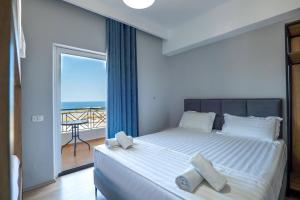 a bedroom with a bed with a view of the ocean at Sunny Hotel in Sarandë