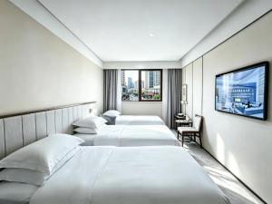a hotel room with four beds and a tv at 威海卫大厦 Weihaiwei Hotel in Weihai +49 photos