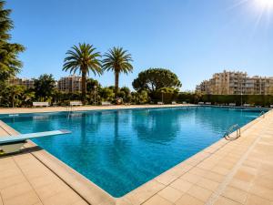 a large swimming pool with palm trees and buildings at La Marina Cannes Suites in Mandelieu-La Napoule