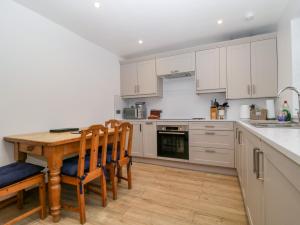 a kitchen with white cabinets and a wooden table and chairs at Capella Cottage in Keswick