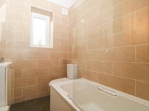 a bathroom with a tub and a toilet and a window at Capella Cottage in Keswick +11 photos