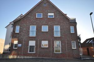a red brick building with white windows on a street at Nr 57 - Ferienwohnung Mühlenstraße in Carolinensiel