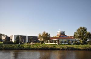 a building with a lighthouse on top of it next to a river at Nr 57 - Ferienwohnung Mühlenstraße in Carolinensiel