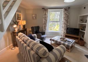 a living room with a couch and a tv at Rubybank Bothy, overlooking Loch Fyne in Strachur