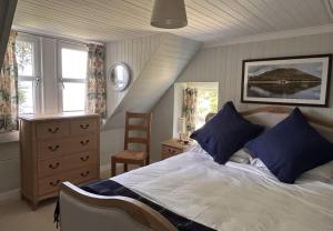 a bedroom with a bed with blue pillows and a chair at Rubybank Bothy, overlooking Loch Fyne in Strachur
