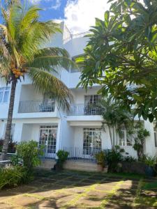 a white building with palm trees in front of it at Appartement hibiscus in Grand-Baie