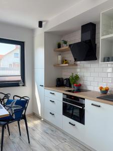 a kitchen with white cabinets and a table and a window at Domki Nord Star in Władysławowo