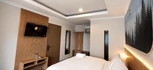 a bedroom with a bed and a tv on a wall at Samara Villa by Sinergi in Tawangmangu