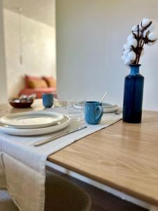 a table with a plate and a blue vase with flowers at Bulle de détente - Proche Disney in Villiers-sur-Morin