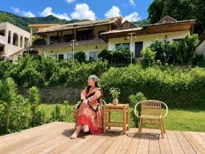 a woman sitting on a deck in front of a house at Lagom home - Cactus in Sapa