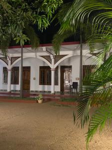 a white building with palm trees in front of it at French Garden Eagle Wings Inn in Trincomalee