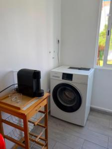 a white washing machine sitting next to a wooden table at Estrela de Almada in Almada