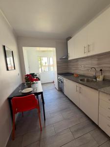 a kitchen with a table and a red chair at Estrela de Almada in Almada