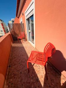 two red chairs sitting on the side of a building at Estrela de Almada in Almada