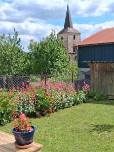 a garden with a bunch of flowers and a church at Maisonnette "Les Volets Bleus" in Orgedeuil