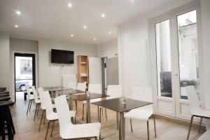 a dining room with tables and white chairs at Enjoy Hostel in Paris