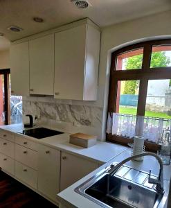 eine Küche mit weißen Schränken, einer Spüle und einem Fenster in der Unterkunft Gordonówka in Choszczno