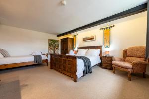 a bedroom with two beds and a chair at Duchy - Treworgie Barton Cottages in Bude +41 photos