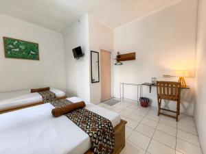 a bedroom with two beds and a table and a chair at Santalum Hotel Yogyakarta in Yogyakarta