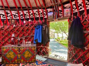 a room with a red wall with a table with a blue shirt at Nomad Garden Camp in Cholpon-Ata