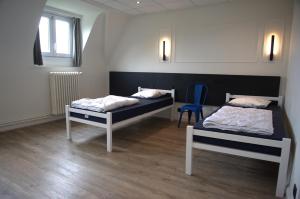 a room with two beds and a blue chair at HI Hostel Dunepanne in De Haan +9 photos