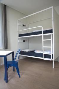 a desk and a chair in a room with bunk beds at HI Hostel Dunepanne in De Haan