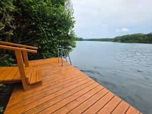 a wooden dock with a bench on the side of a lake at Landhaus am See - Gästezimmer in Strausberg